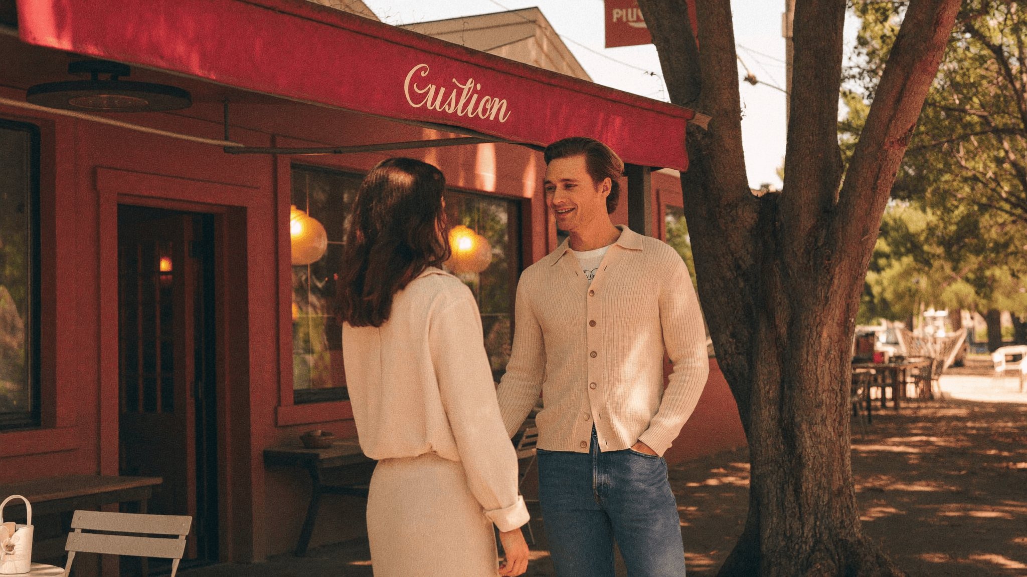 Two people meeting at an Austin cafe in late afternoon, candid moment of recognition
