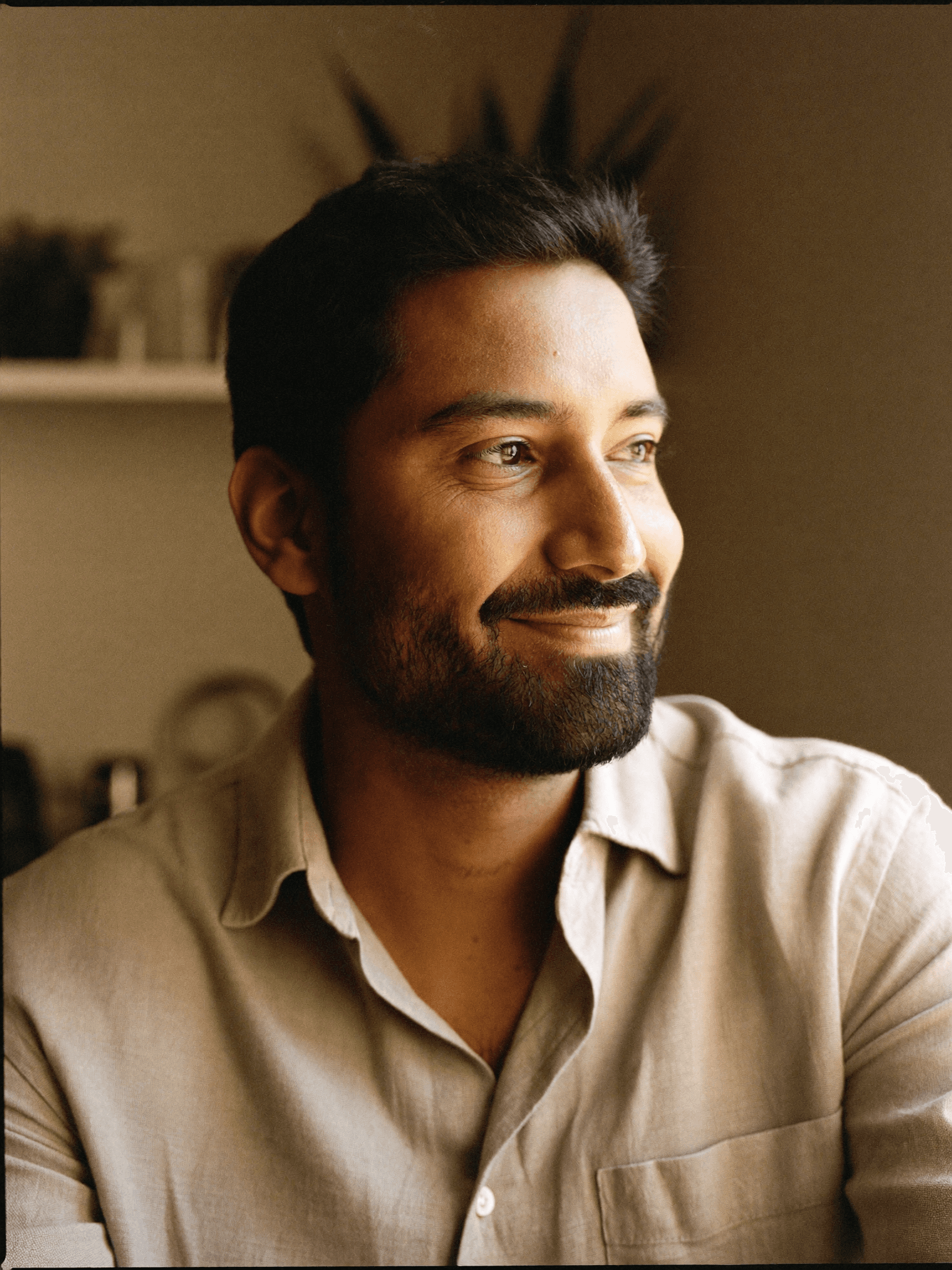 Man in his late twenties with a quiet warm smile, simple oatmeal linen shirt